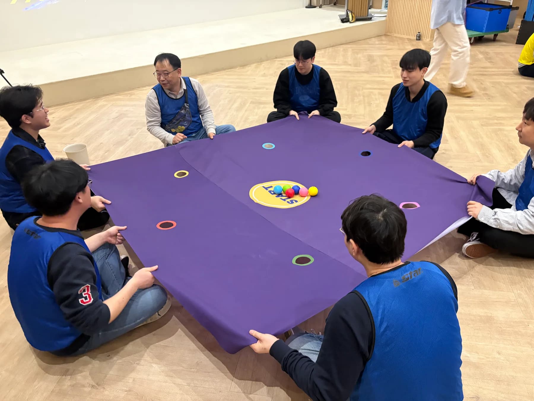 파란 팀 참가자들이 여러 색 공을 같은 색 구멍으로 이동시키는 실제 팀빌딩 현장